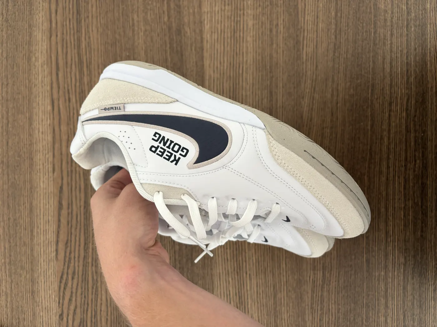 White boot held in hand showing a Keep Going transfer above the swoosh