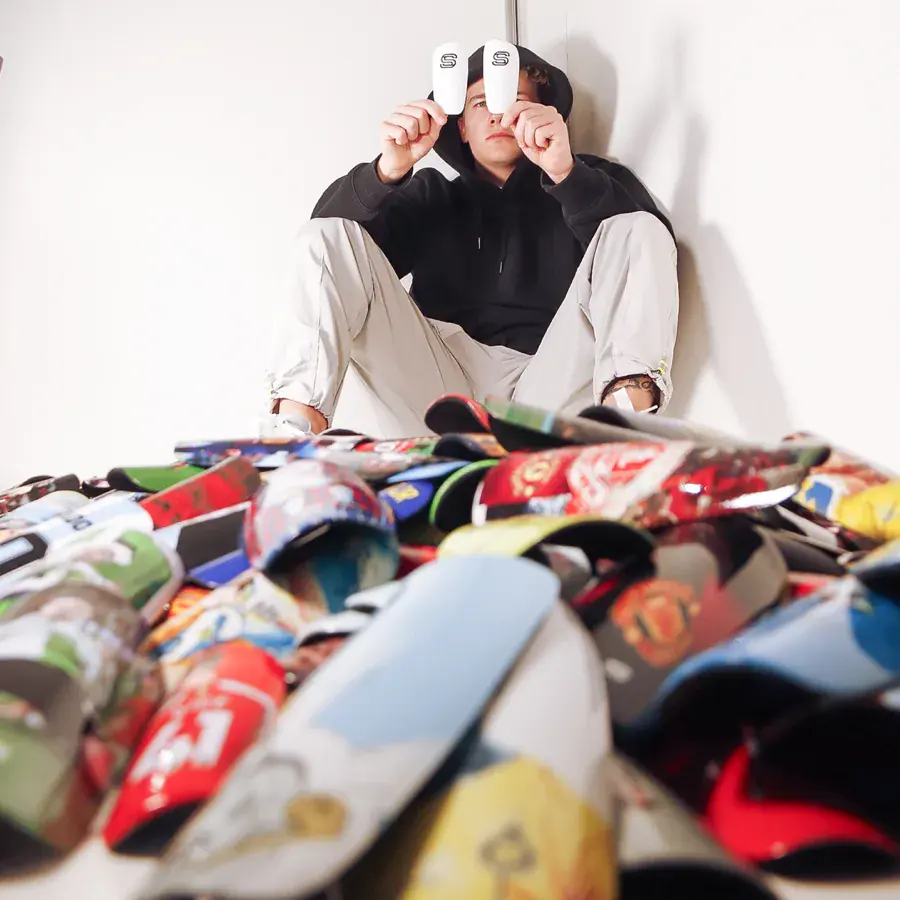 Strapzy's co-founder holding two white S shin pads behind a pile of custom pads