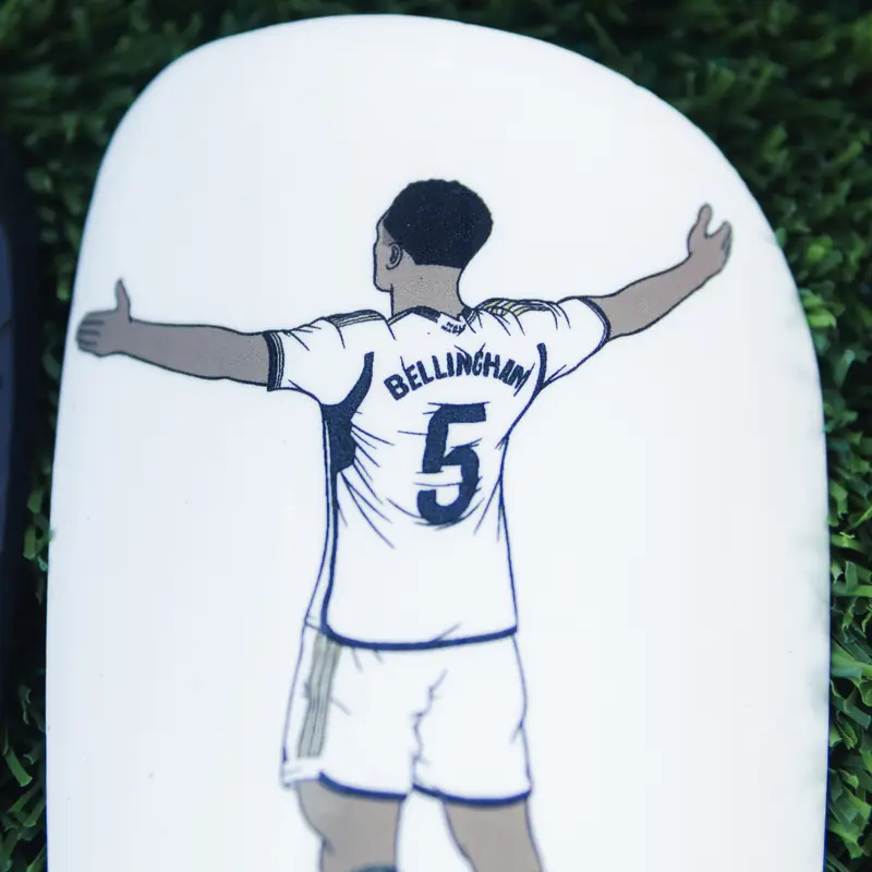 White custom shin pad with a line-drawn player celebrating